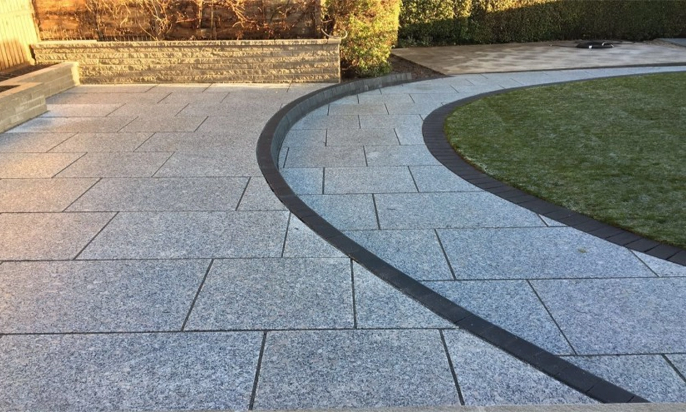 Granite pavers forming a beautiful and durable pathway with a curved design and green grass alongside.