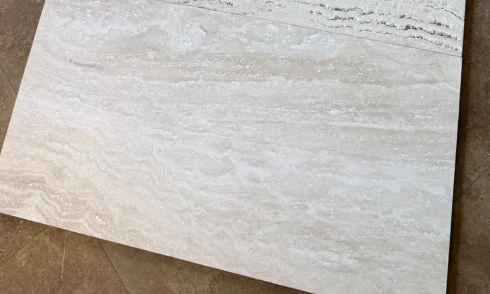Natural travertine stone flooring with irregular shapes and light beige tones, showing a close-up of surface texture.