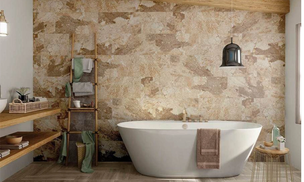 A cozy bathroom with a freestanding tub, natural limestone tiles on the wall, and a bamboo ladder shelf holding towels. The warm textures create a tranquil, earthy atmosphere.