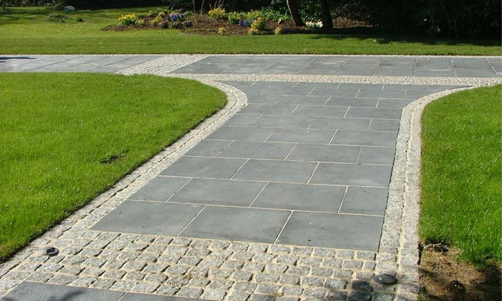 A pathway made of stone pavers, creating a clean and stylish outdoor walkway with a grassy border.