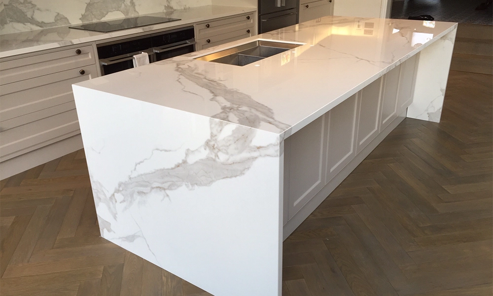 “Sleek modern kitchen island with white quartz stone countertop featuring subtle gray veining.”