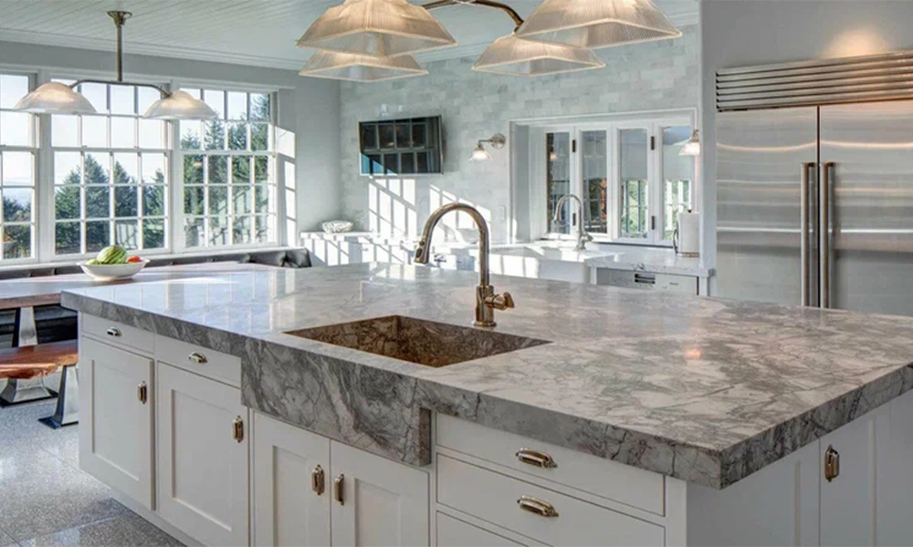 Modern kitchen interior with elegant gray marble countertop and brass faucet on white cabinets.