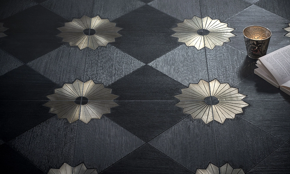 Decorative dark-colored tile floor featuring a flower-like design with metallic accents in the center.